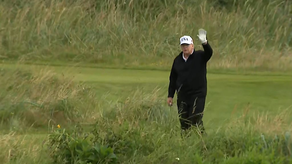 Trump gives the cameras a wave while playing golf at Turnberry